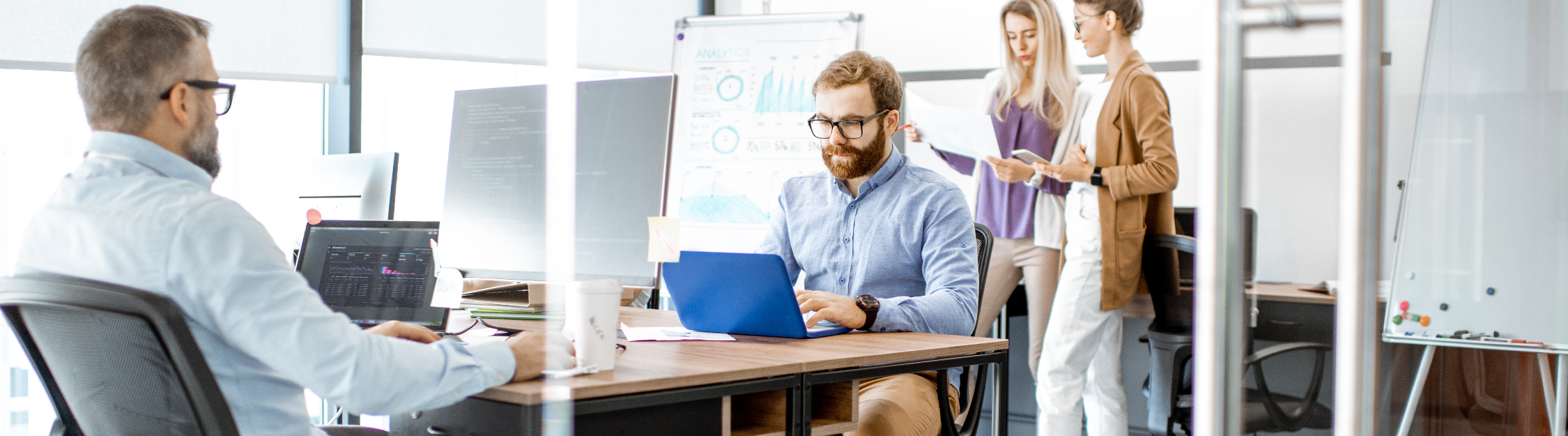 Multiple people work on various devices in small modern office space