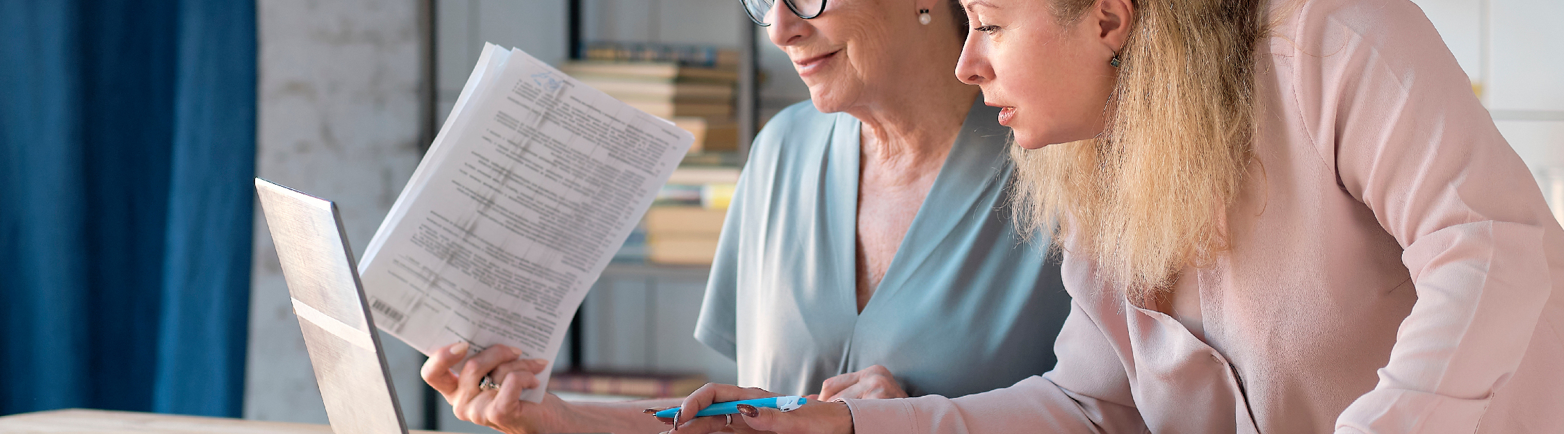 Adult daughter helps golden-age mother on laptop at home