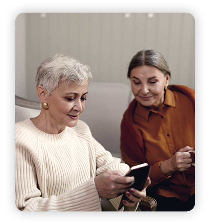 Two mature women use phones together